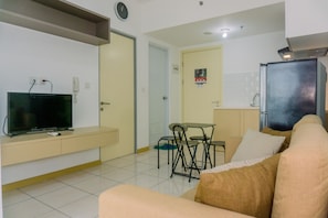 A living room with a TV, sofa, and a dining area with chairs and a table.