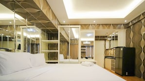 A hotel room with a large bed, a wardrobe, a desk, and a refrigerator.