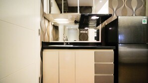 A modern kitchen with a stainless steel refrigerator, a black range hood, and a white sink.