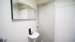 Un ba ño con un lavamanos blanco, un espejo y una puerta.