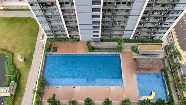 Ein Hochhaus mit Wohnungen und einem Dachpool, umgeben von Grünflächen und einer kleinen Gartenanlage.
