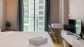 Ein Hotelzimmer mit Bett, Schreibtisch mit Computer, Fernseher und einem fenster mit Vorhängen.