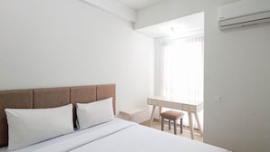 A hotel room with a bed, a desk, and an air conditioning unit. - Modern Studio At Barsa City Apartment (Yogyakarta)