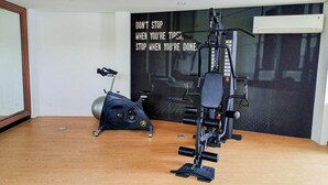 A home gym with an exercise bike, a stationary bike, and a multi-functional exercise machine. - Modern Studio At Barsa City Apartment (Yogyakarta)