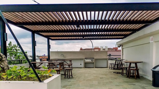 A rooftop patio with outdoor seating, a grill, and a view of the city skyline. - Modern Studio At Barsa City Apartment (Yogyakarta)