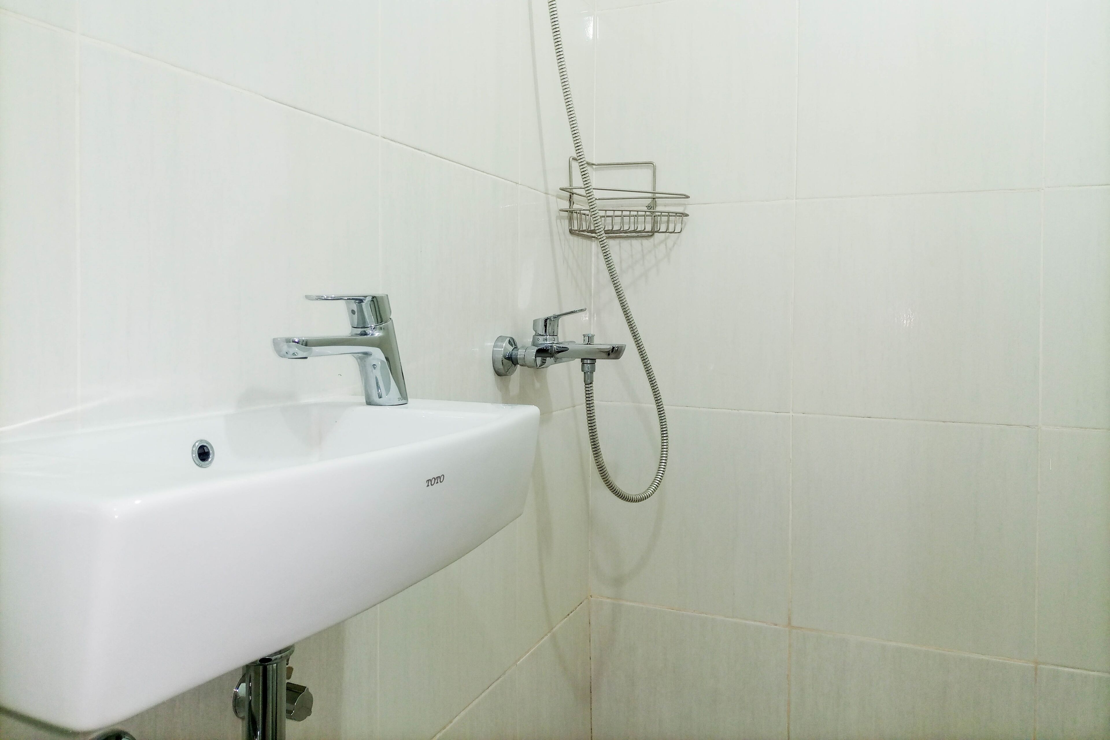 A bathroom with a white sink, a handheld showerhead, and a metal towel rack.