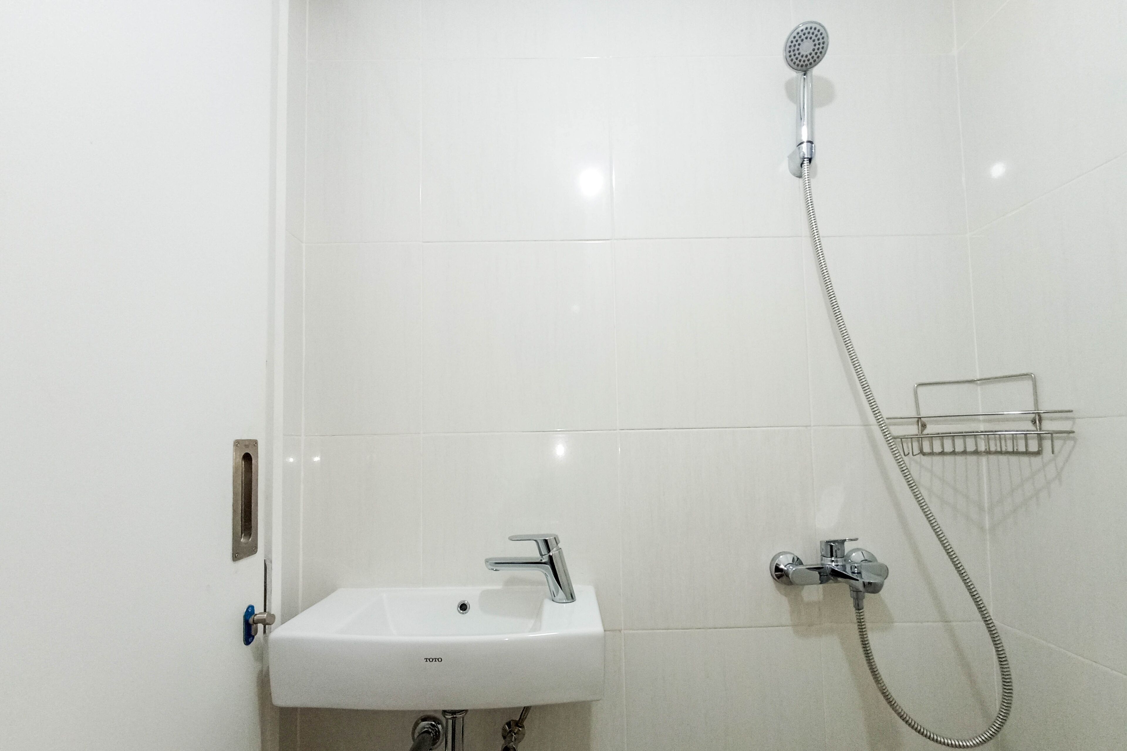 A bathroom with a white sink, a handheld showerhead, and a towel rack.