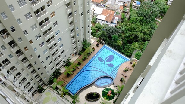 An aerial view of a high-rise building with a rooftop swimming pool featuring a leaf design. - Good Deal 1Br Apartment At Parahyangan Residence (Bandung)