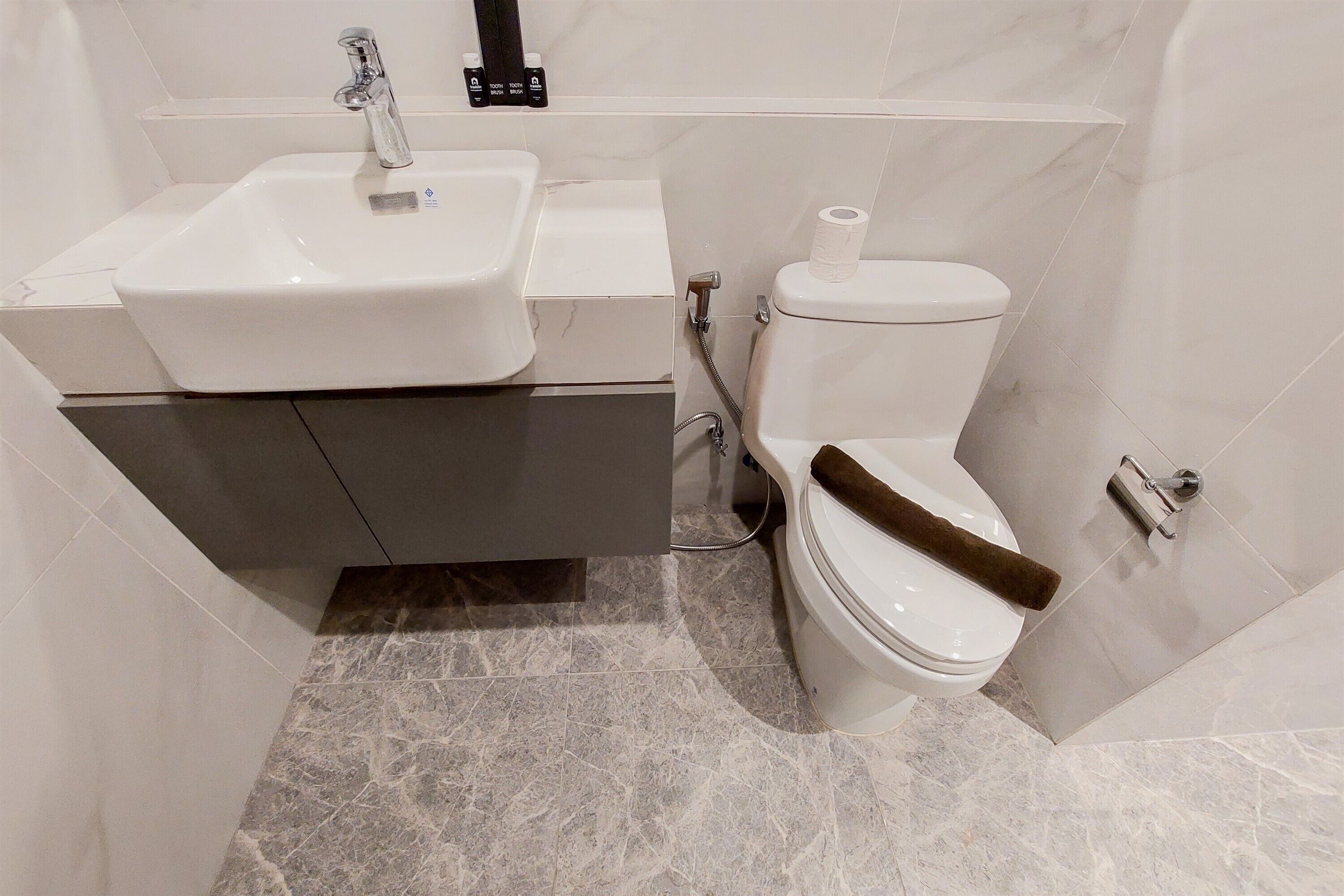 A bathroom with a white sink, toilet, and marble flooring.