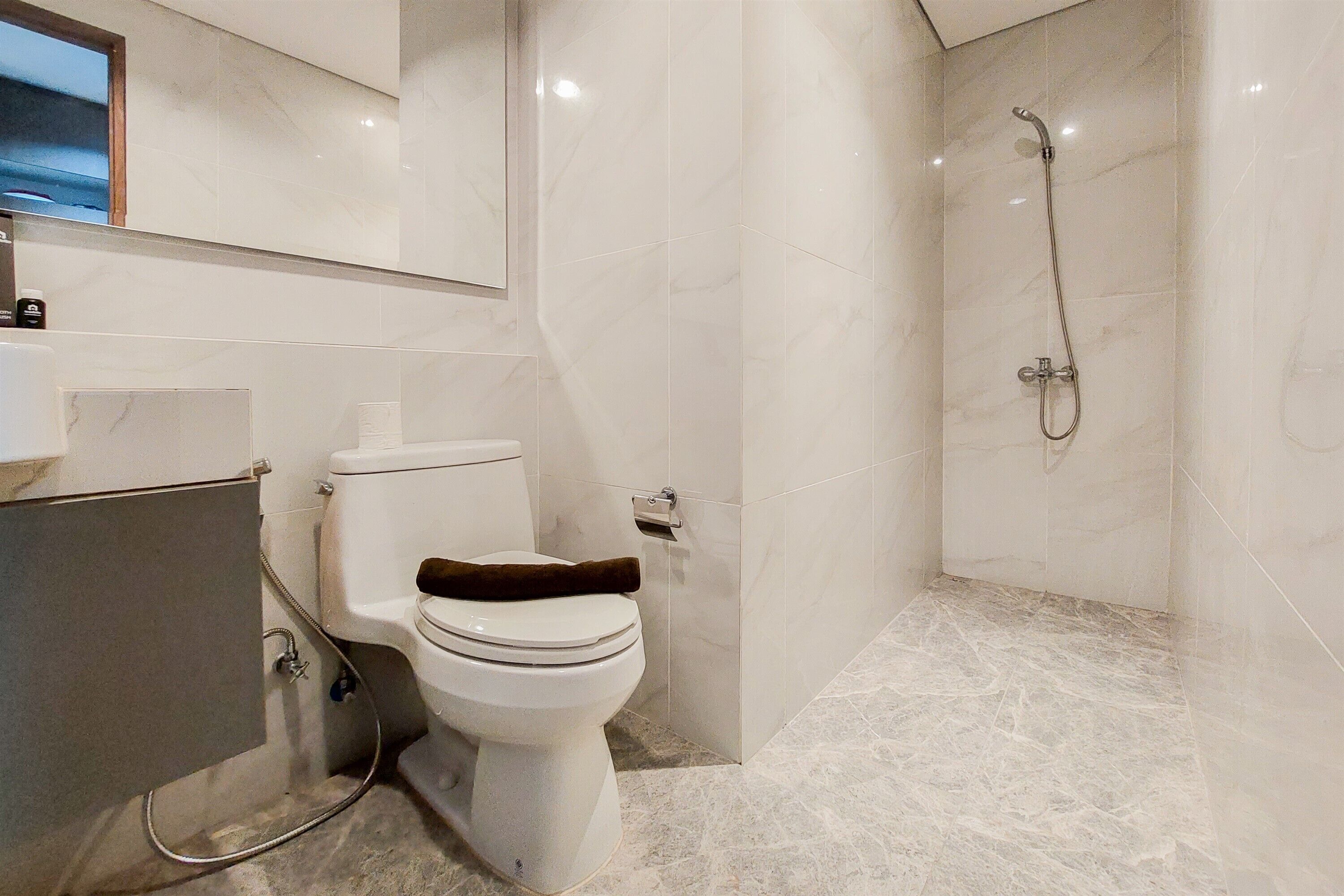 Une salle de bain avec des toilettes, une douche et un sol en marbre.
