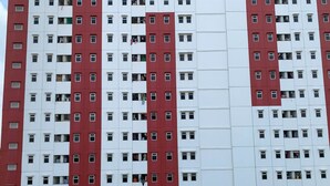 A multi-story building with a red and white facade, featuring numerous windows and balconies. - Cozy 2Br At Delta Cakung Apartment (Jakarta)