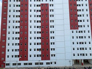 A multi-story building with a red and white facade, featuring numerous windows and balconies.