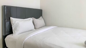 A bed with a grey headboard and white bedding. - Cozy 2Br At Delta Cakung Apartment (Jakarta)