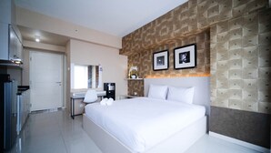 A hotel room with a bed, a desk, a chair, a mirror, and a wall with geometric patterns.