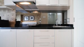 A modern kitchen with a black countertop, beige cabinets, and a stainless steel sink.