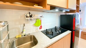 Une cuisine moderne dotée d’un évier en acier inoxydable, d’une cuisinière à gaz, d’un réfrigérateur noir et d’armoires en bois.