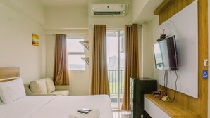 A hotel room with a bed, a TV, a desk, and a window with curtains.