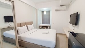 Moderni hotellihuone, jossa on sänky, työpöytä, televisio ja peili.