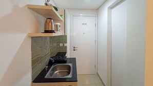 Kompakti keittiö, jossa on musta työtaso, ruostumattomasta teräksestä valmistettu pesuallas ja valkoinen ovi, jossa on kahva.