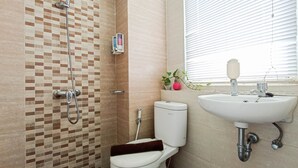A bathroom with a shower, toilet, sink, and window. - Classic Studio At Student Castle Yogyakarta Apartment (Depok)