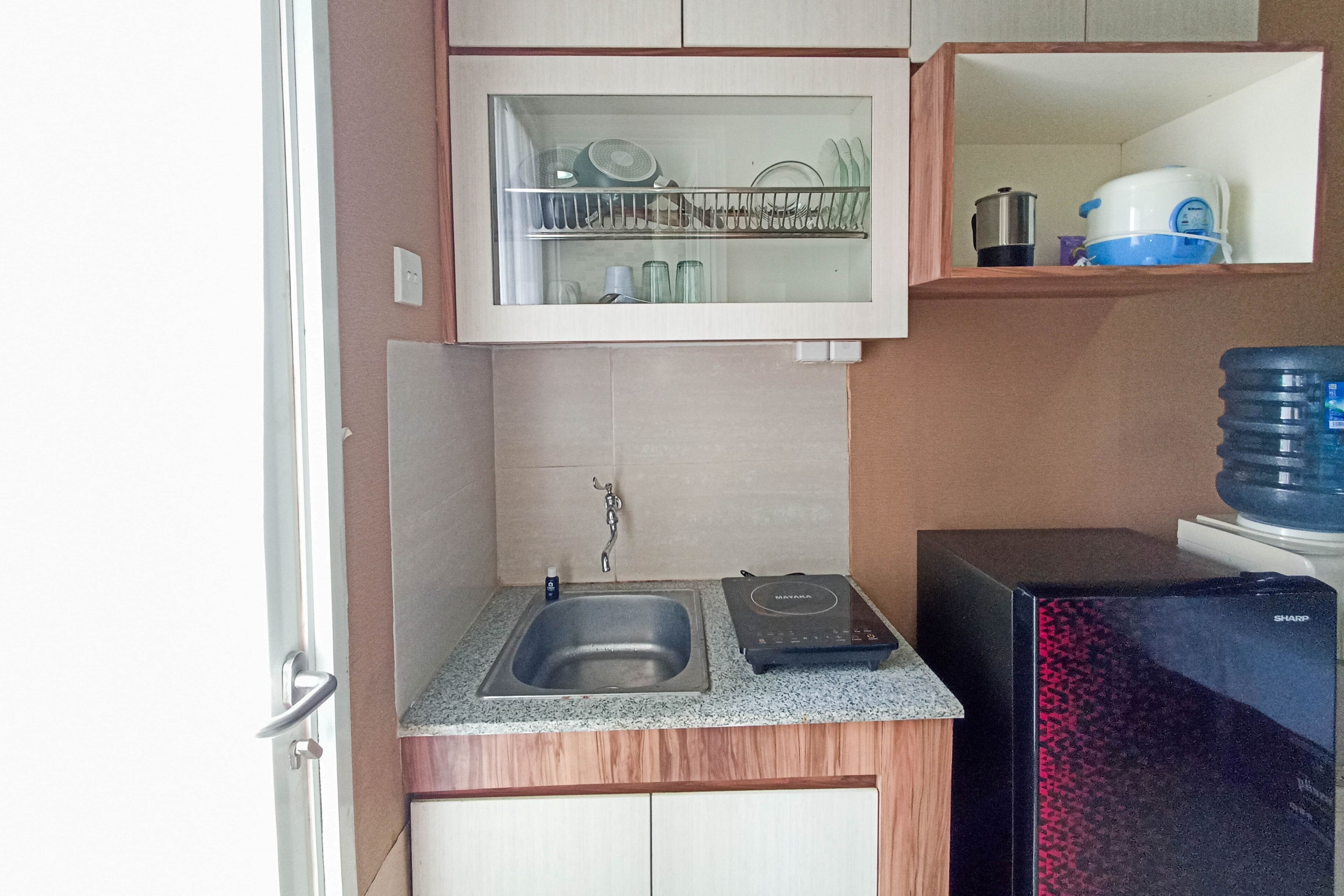 A compact kitchen with a built-in sink, a microwave, and a water dispenser.