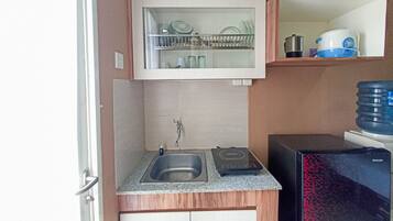 A compact kitchen with a built-in sink, a microwave, and a water dispenser.
