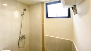 A bathroom with a shower, a window, and a ceiling-mounted air conditioning unit.