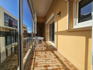 A balcony with a glass door, a table with chairs, and a view of neighboring buildings.