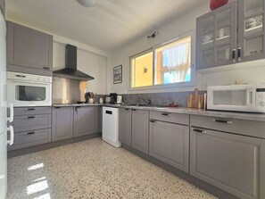 A compact kitchen with grey cabinets, a built-in oven, a microwave, and a dishwasher.