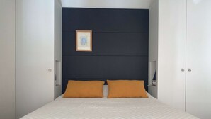 A bedroom with a bed, two pillows, a framed picture on the wall, and a wardrobe. - T1 Loft with Air Conditioning, Parking and Wifi in Balaruc-les-Bains (Balaruc-les-Bains)