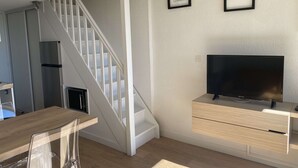 A modern living room with a staircase, a flat-screen TV, and framed artwork on the wall. - T1 Loft with Air Conditioning, Parking and Wifi in Balaruc-les-Bains (Balaruc-les-Bains)