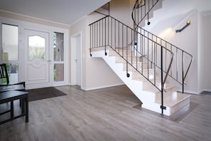 A modern interior with a spiral staircase, light wood flooring, and a dining area with a table and chairs.