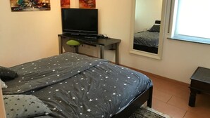 Une chambre à coucher avec un lit, un téléviseur posé sur un meuble et des œuvres d’art accrochées au mur.