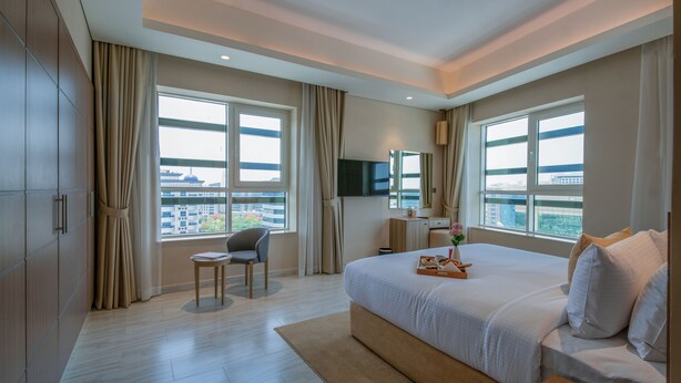 Ein modernes Hotelzimmer mit einem großen Bett, einem Schreibtisch, einem Sessel und einem Fernseher.