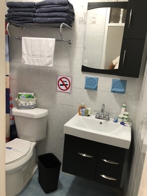 Un baño con inodoro, lavabo y toallas apiladas.