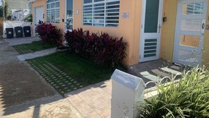 Un edificio con fachada amarilla, techo de tejas y entrada protegida por una reja.