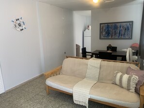 Una sala de estar con un sofá color beige, una manta y un adorno de timón de barco en la pared.
