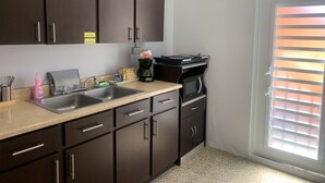 Una cocina con gabinetes oscuros, un fregadero, una cafetera y un microondas.