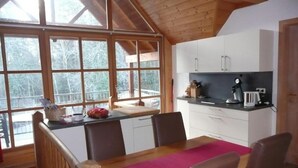Una cocina con techo de madera, ventanas grandes y un comedor con alfombra rosa.