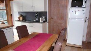 Una cocina compacta con una mesa de comedor, sillas, un refrigerador y un microondas.