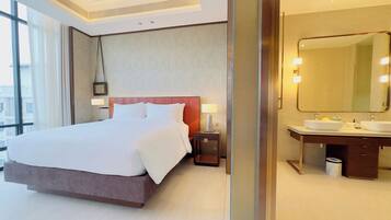A hotel room with a large bed, a bathroom with a mirror, and a view of the city.
