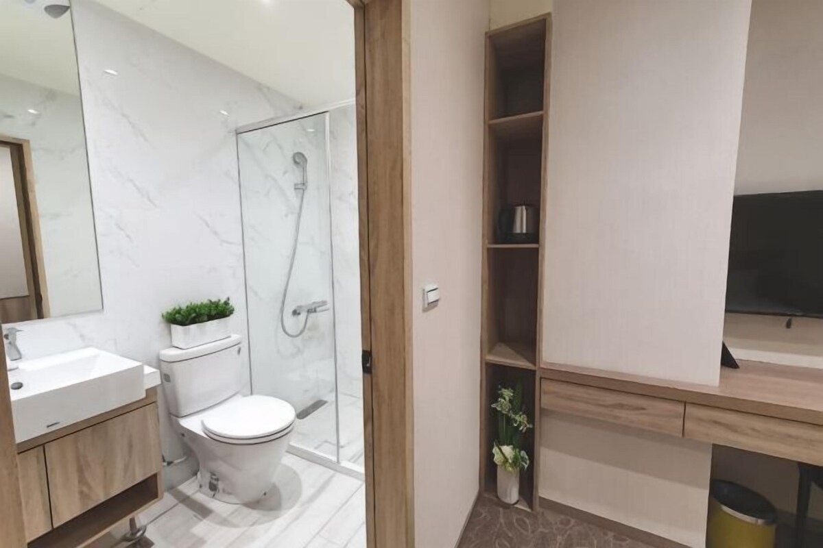 Un baño moderno con inodoro, ducha y un estante empotrado con una planta.