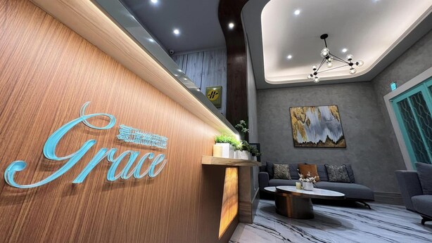 Una zona de recepción con un mostrador de madera, una lámpara moderna y un sofá gris.