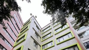 Un edificio de varios pisos con fachada verde y azul, un escaparate con un personaje de dibujos animados y un cartel que dice 'City Tour Smile Hotel'.