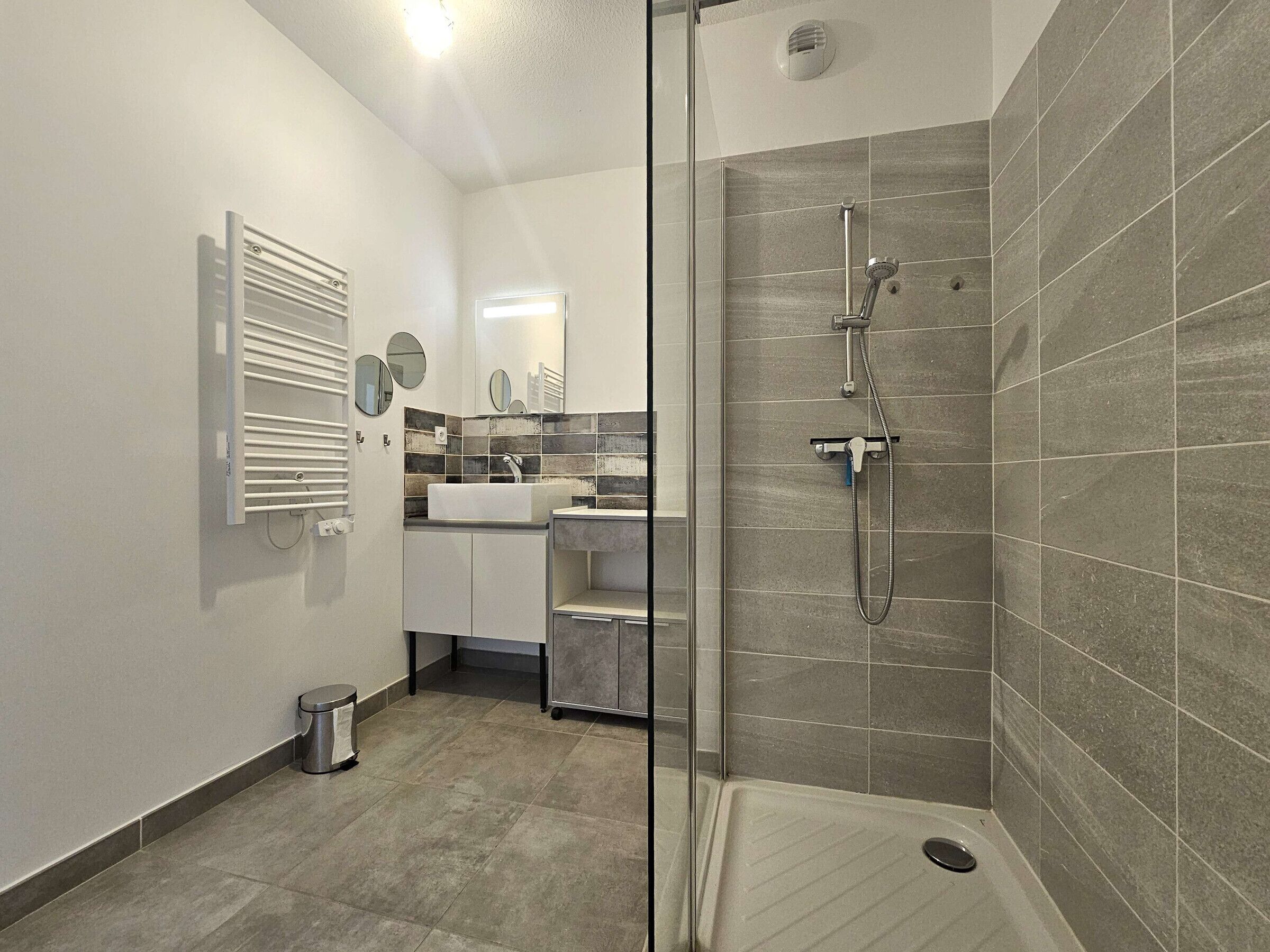 A modern bathroom with a shower, a sink, and a toilet.
