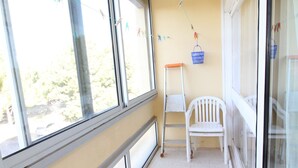 A room with large windows, a white chair, a ladder, and a blue basket hanging on the wall. - Bright 1-Bed Apt near Thermal Baths, Equip’d Kitchen, WiFi, Parking, 2-Star Rated, 45m² (Balaruc-les-Bains)