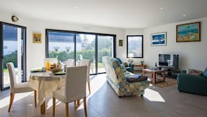 Een ruime woonkamer met een eettafel, stoelen, een bank en een televisie.