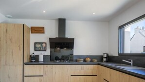 Een moderne keuken met houten kastjes, een zwart aanrechtblad en een raam met uitzicht.