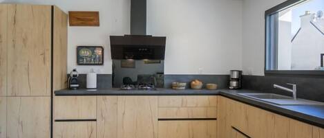 A modern kitchen with wooden cabinets, a black countertop, and a window providing a view of the outside.