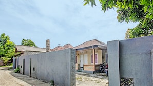 Een rij huizen met betonnen muren en pannendaken, met een motorfiets ervoor, en een heldere lucht.